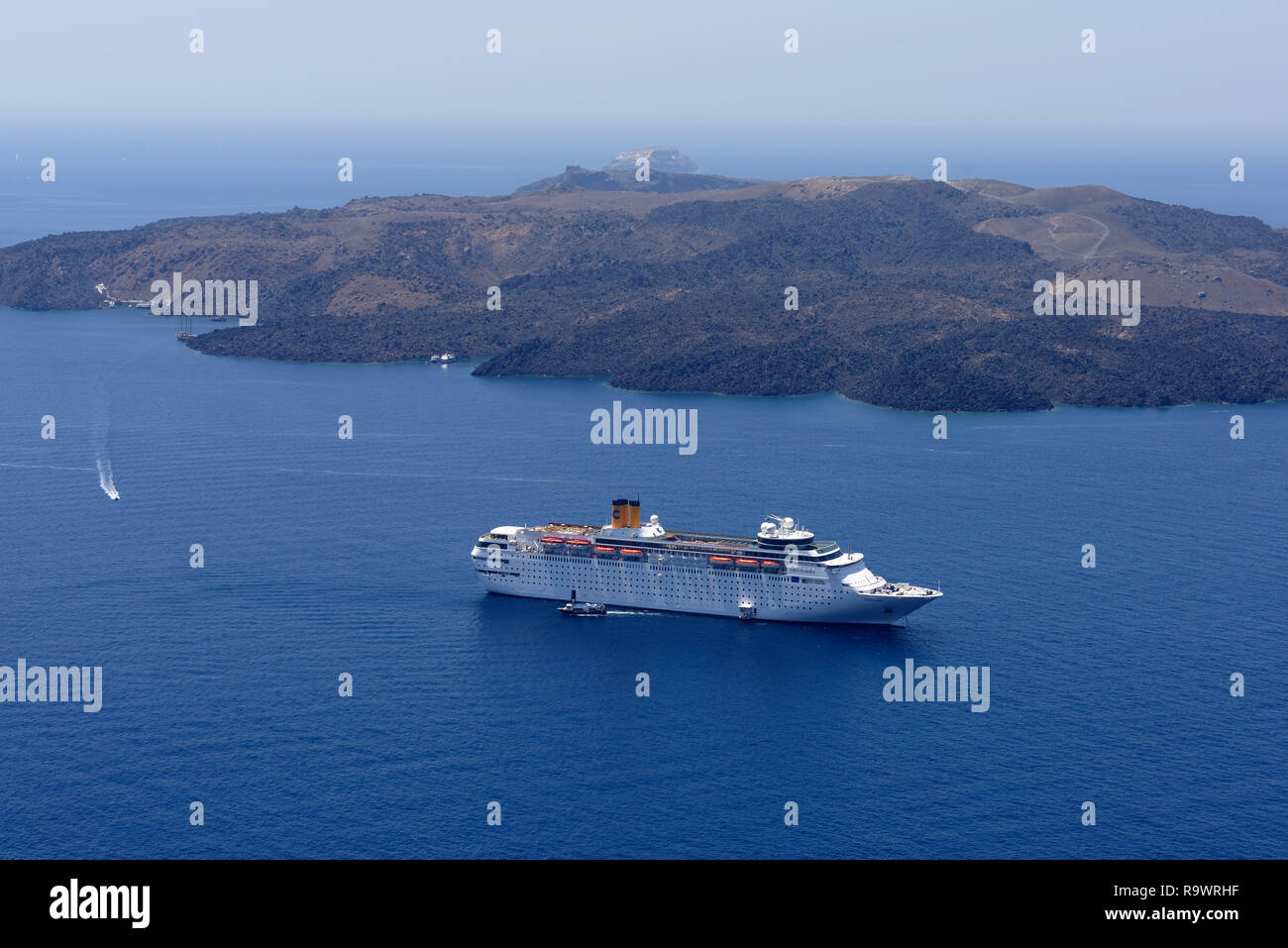 The cruise ship Costa Classica in the deep azure blue waters of the Caldera of Santorini, Greece. In the background is Nea Kameni, the largest of the  Stock Photo