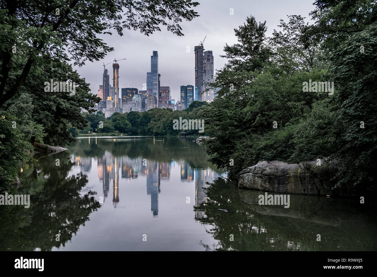 New York City skyline from Central Park with water reflections at dusk ...