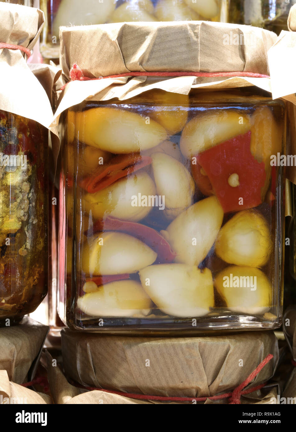 glass jar with garlic cloves with red peppers in oil on sale in the