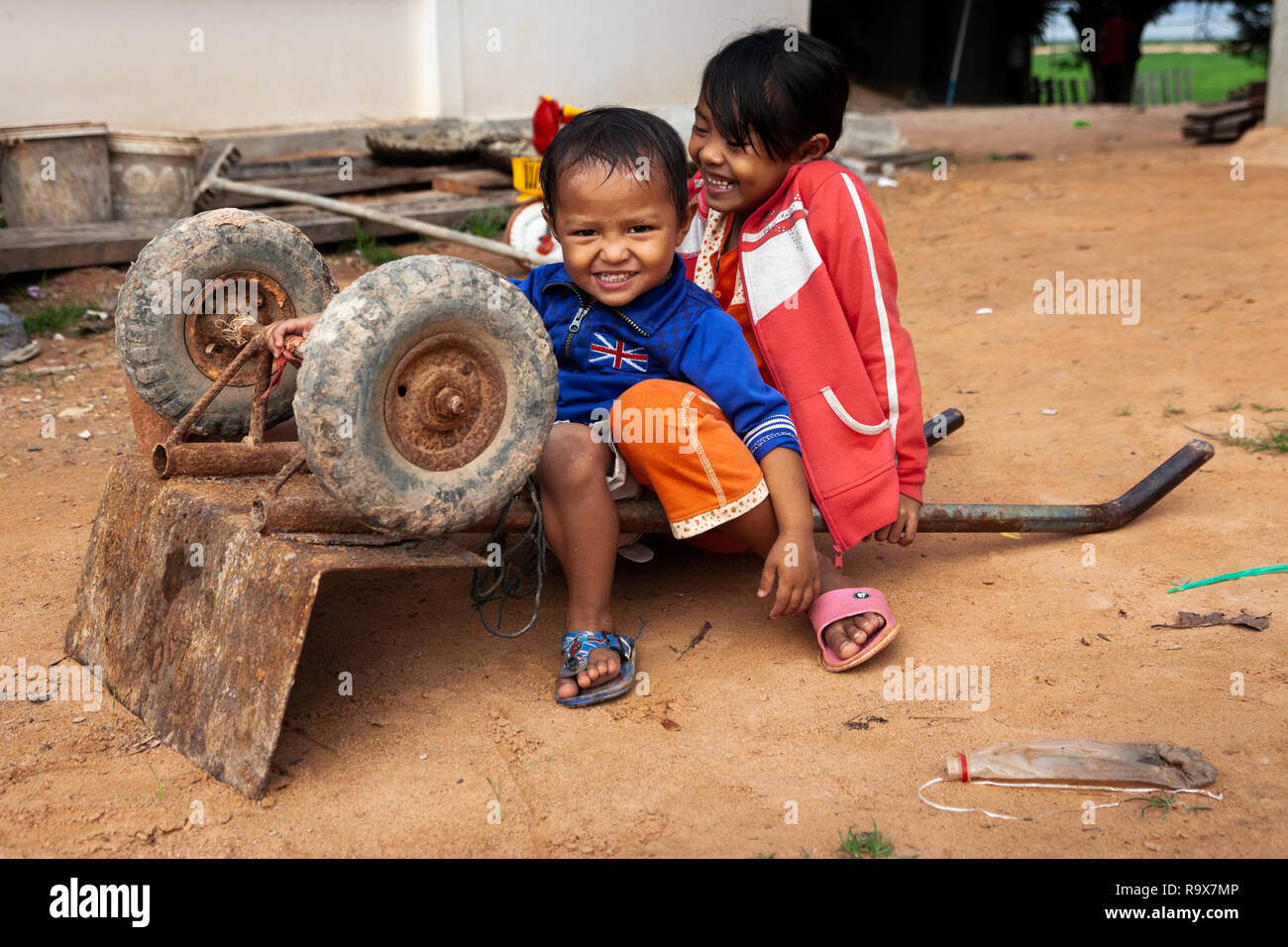 Two kids playing with a wheelbarrow outside Stock Photo