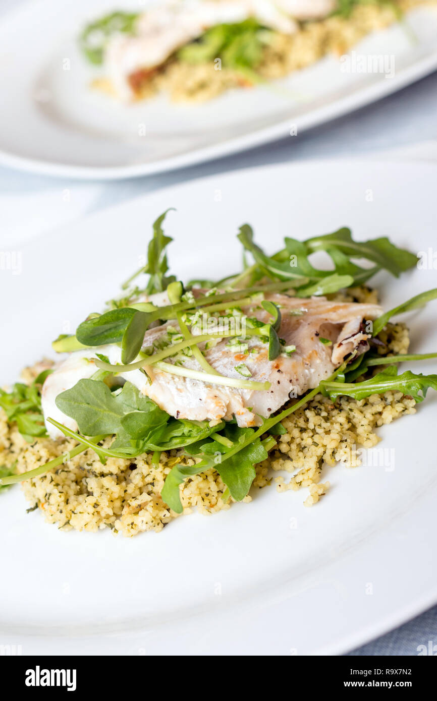 cooked sea bass  fish fillet dish with greens and couscous Stock Photo