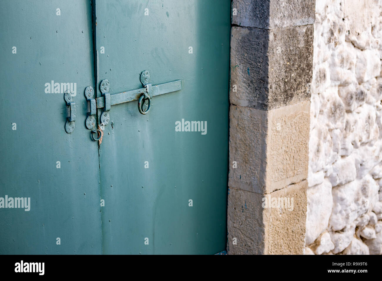 Selective focus on grungy closed blue metal door with slider lock, partial side view. Corfu, Kerkira Island, Greece, springtime day details picture Stock Photo