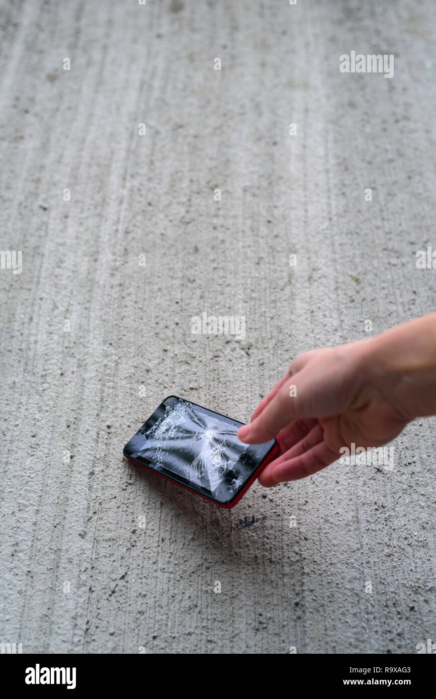 Hand holding phone with broken screen by hammer Stock Photo