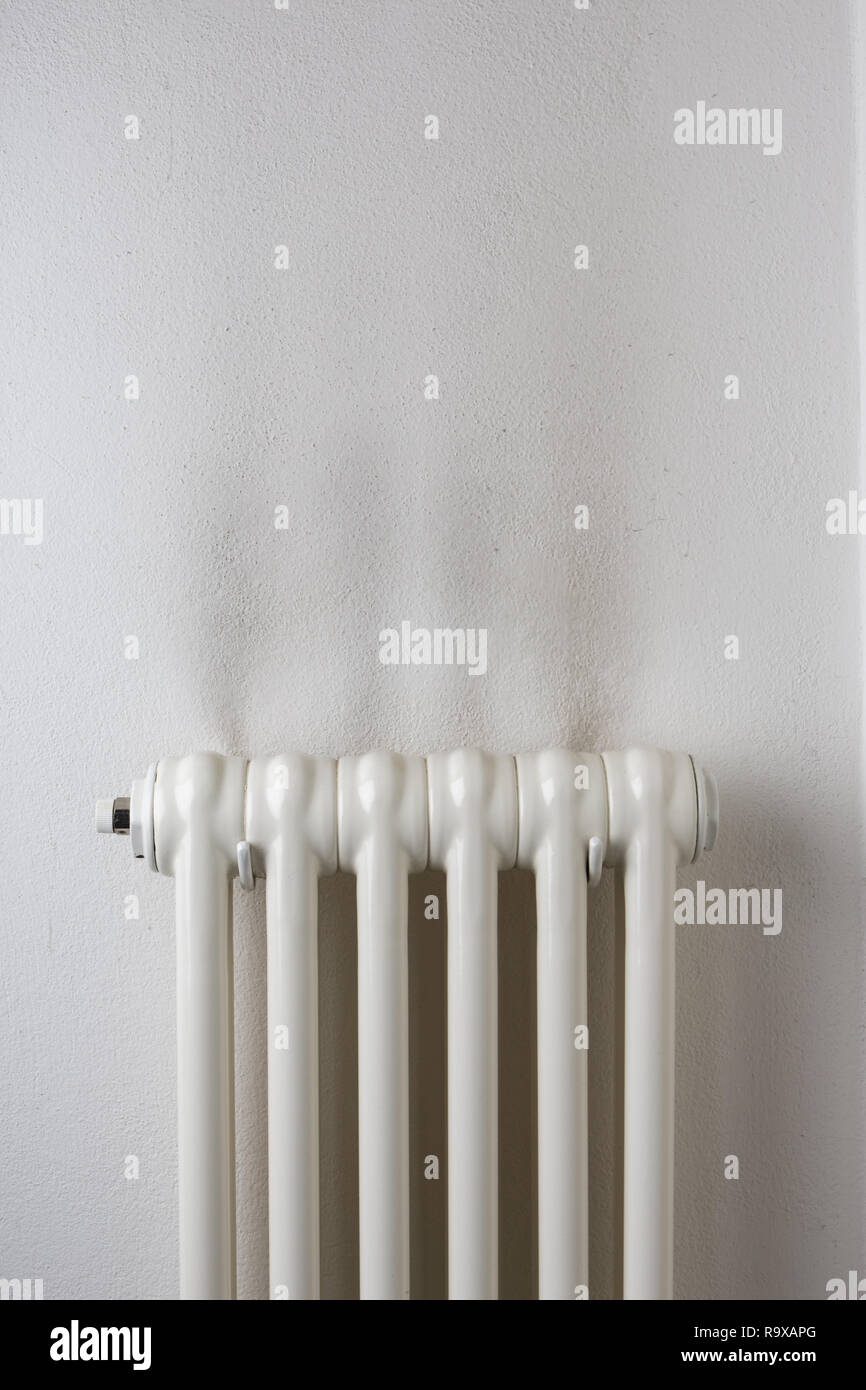 Dark stains on a wall above a household heat radiator Stock Photo