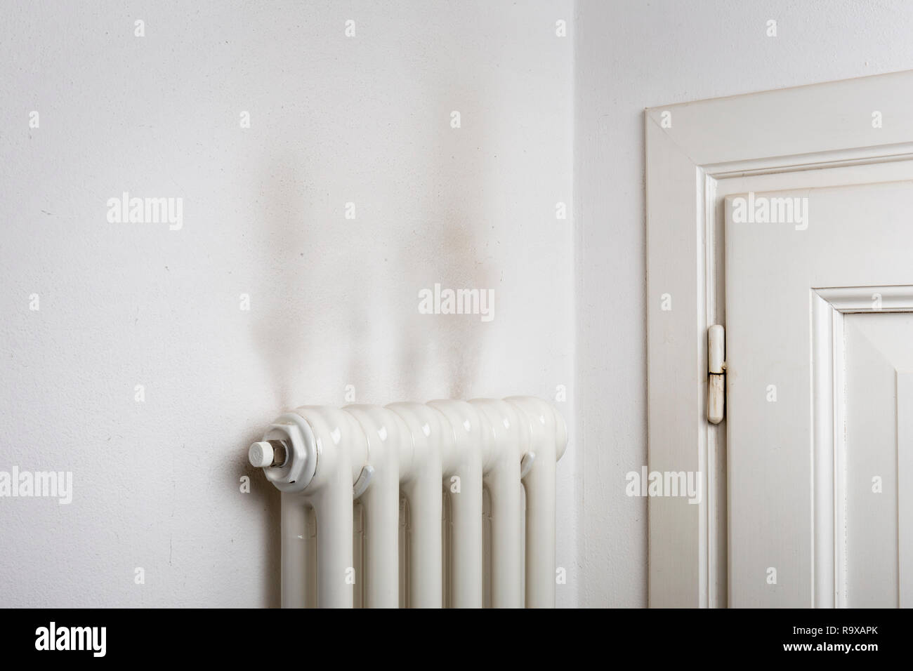 Dark stains on a wall above a household heat radiator Stock Photo