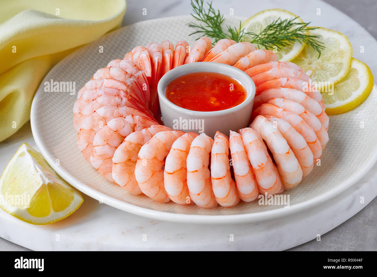 Close-up on shrimp ring with sweet chili sauce on marble serving board with yellow towel on light background Stock Photo