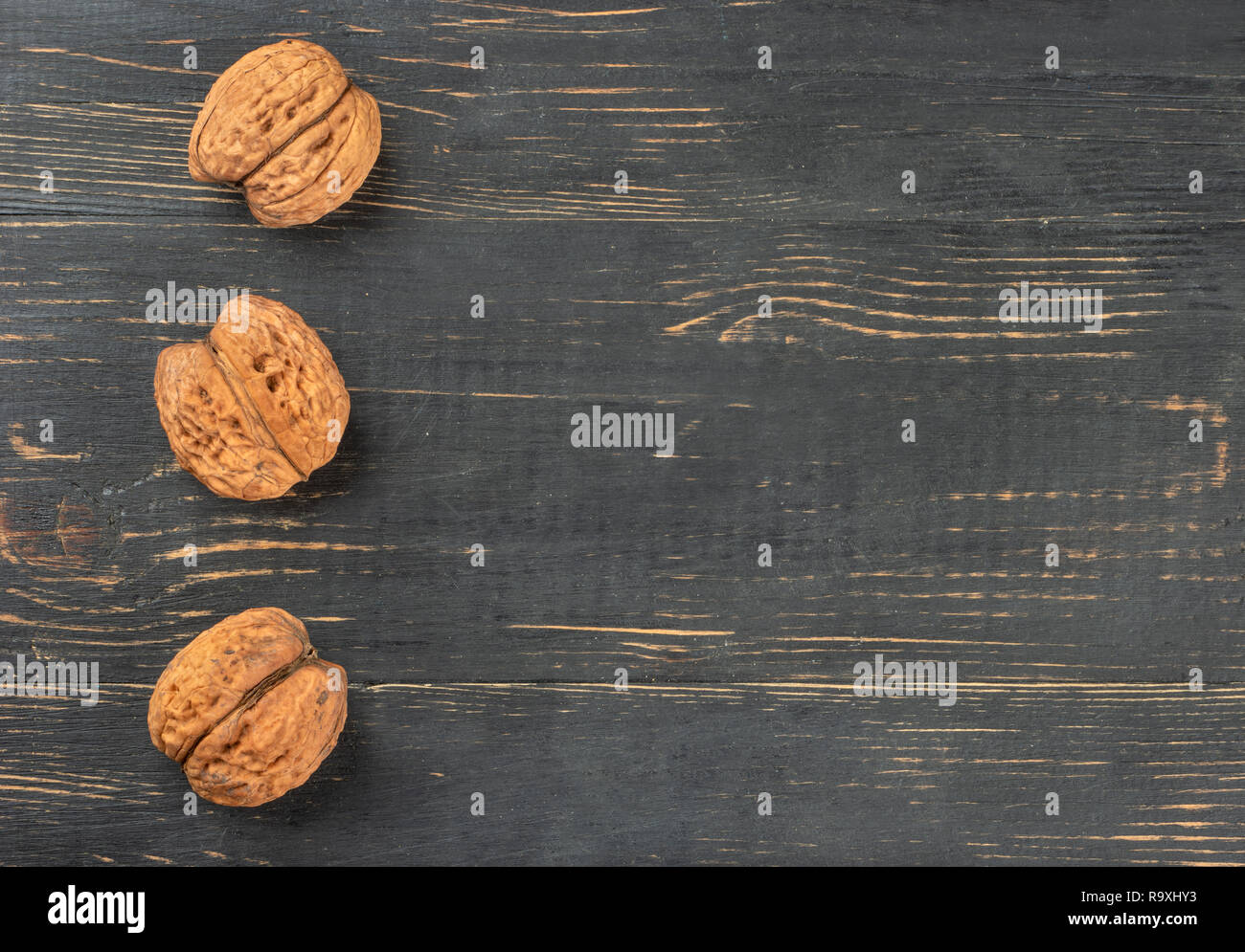 Three dry walnuts on an empty wooden background, top view Stock Photo