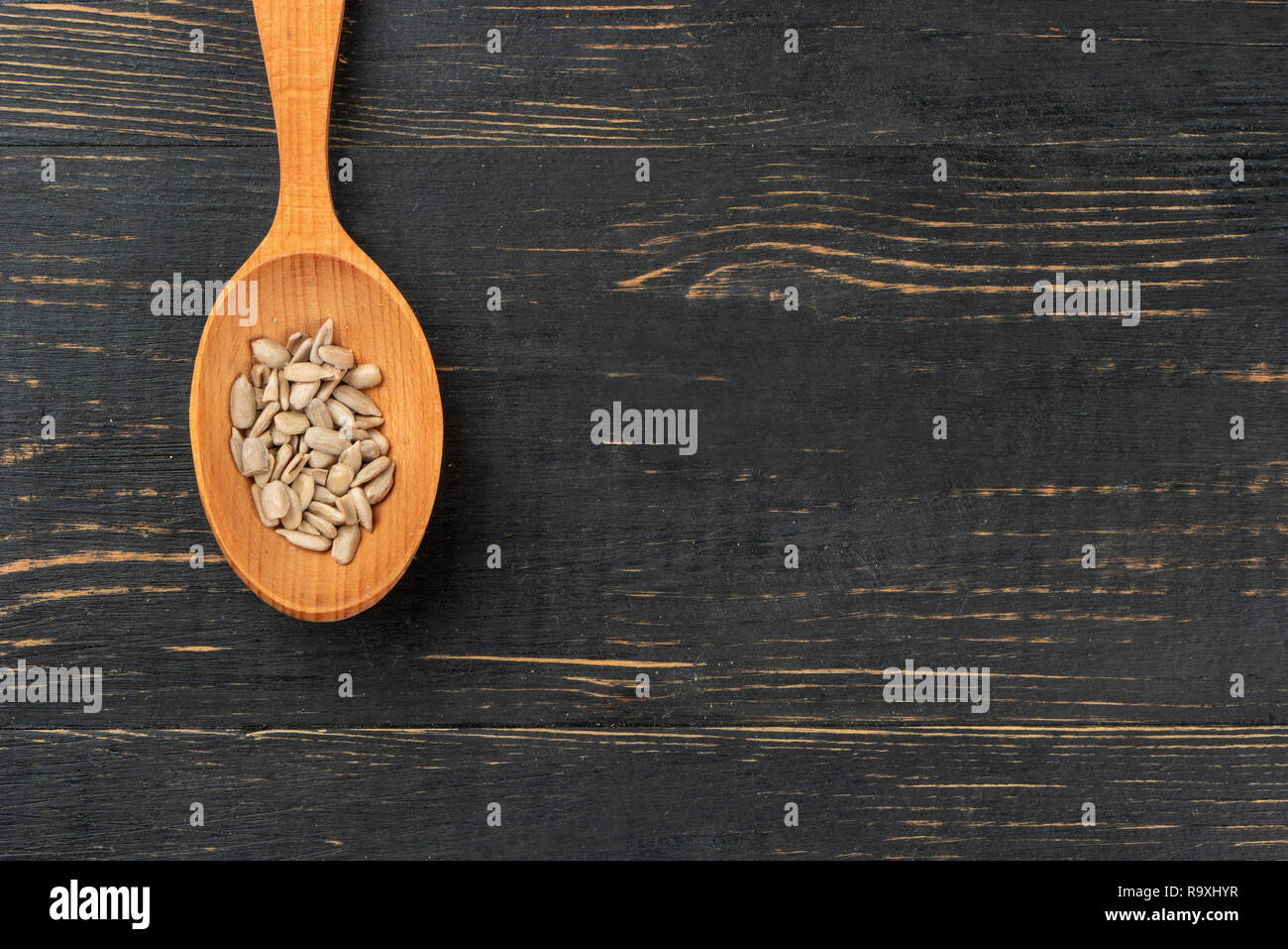 Sunflower seeds without shell in a spoon on an empty wooden background