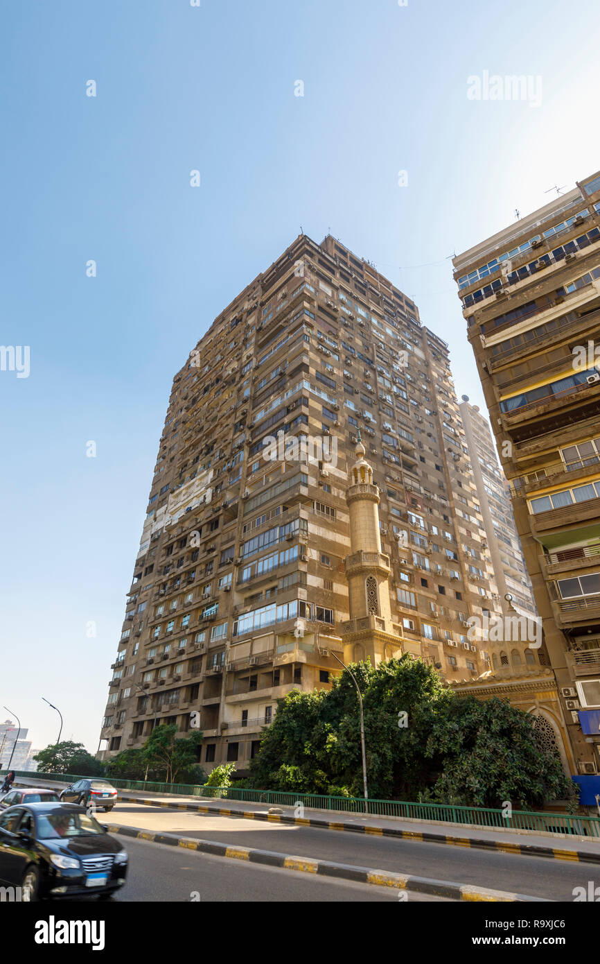 Street scene in Giza, Cairo, Egypt, typical large roadside residential apartment block with external air-conditioning units and a small mosque minaret Stock Photo