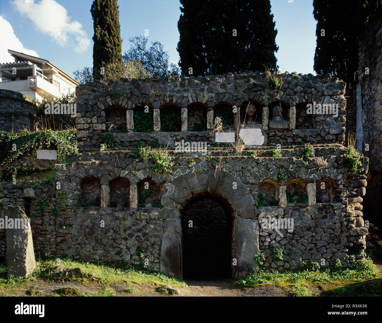 Italy. Pompeii. Necropolis of Nocera Gate. Located on the sides of a road that runs parallel with the city walls. There are several burial monuments. 1st century BC-1st century AD. Tomb 70S of Publius Flavius Philoxsenus and Flavia Agathea. The facade with niches still retains some busts and plaques with inscriptions. Late republican era. 50-30 BC. Campania. Stock Photo