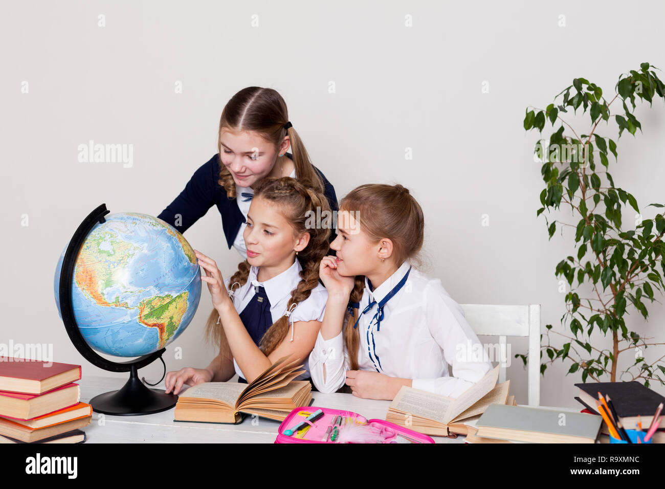 three girls in the school geography lesson learn globe Stock Photo - Alamy