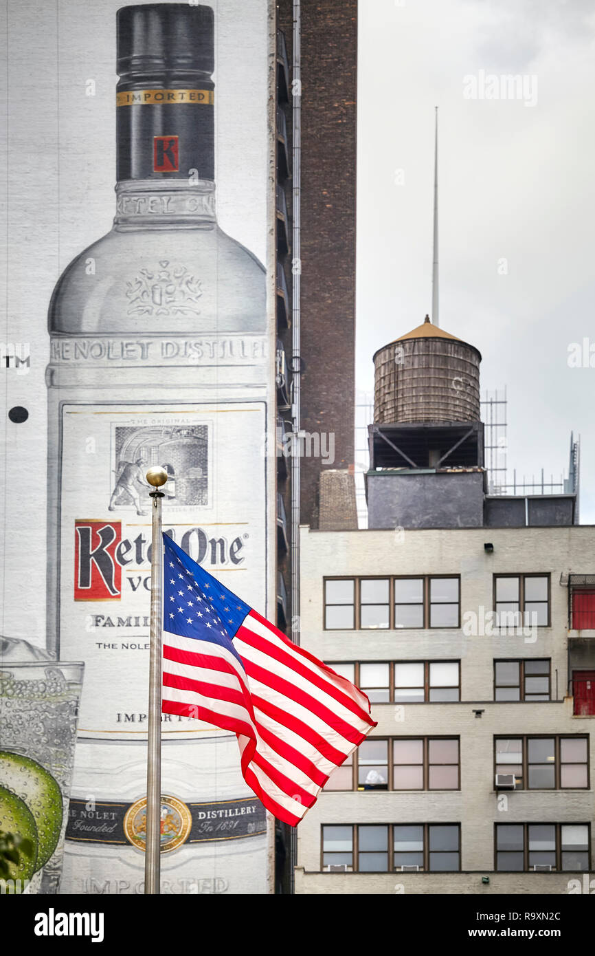 New York, USA - June 28, 2018: Flag of the United States of America with Ketel One Vodka banner and water tank in background in downtown Manhattan. Stock Photo