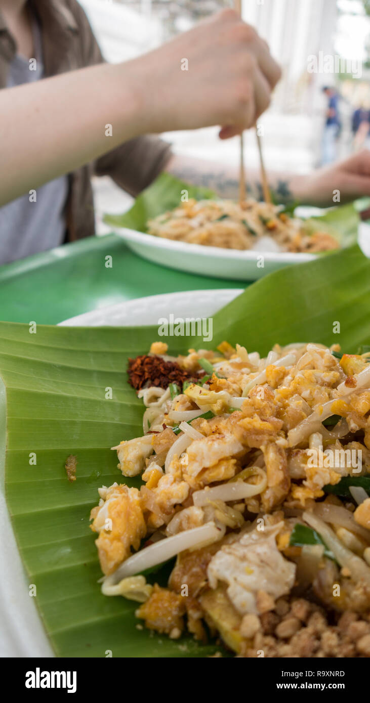 Meal of pad thai noodles on a banana leaf plate at a street food stall in Bangkok, Thailand Stock Photo