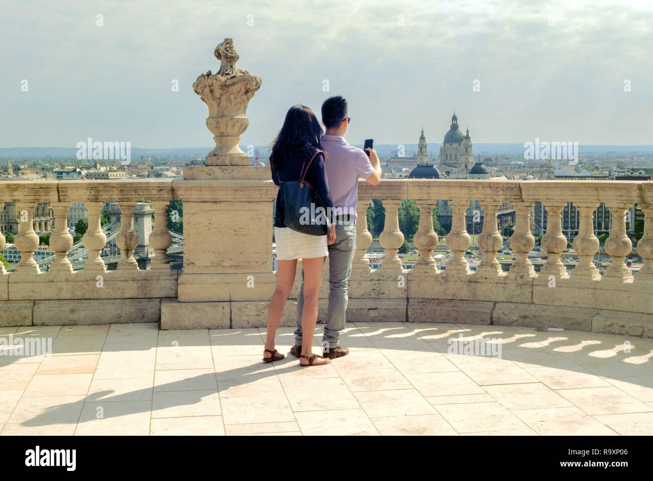 Young couple of Asian ethnicity is making selfie on Royal Palace terrace  against Budapest view Stock Photo