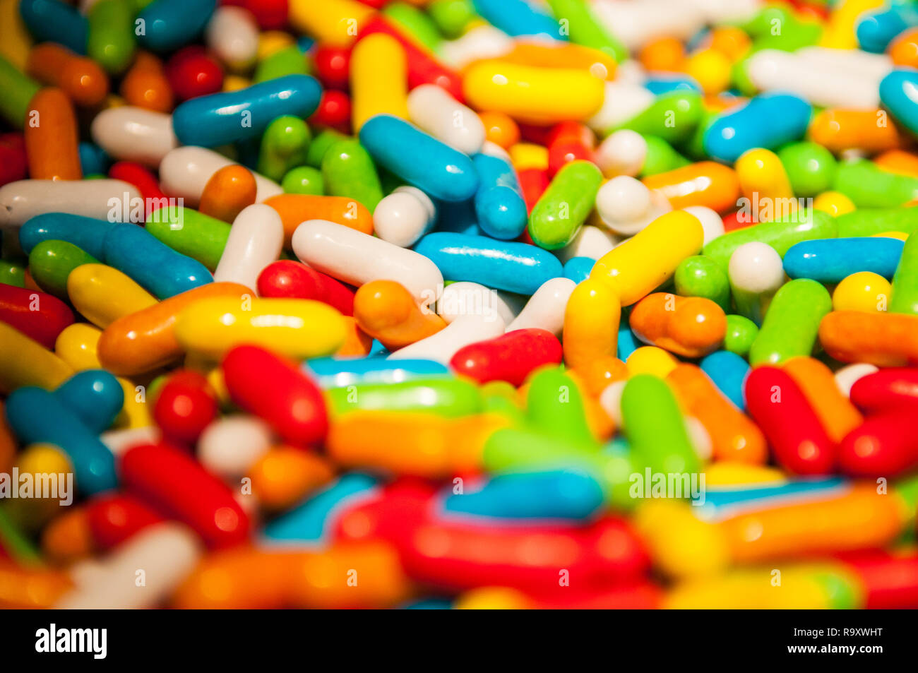 Close up of hundreds of  multi-coloured vibrant colourful liquorice torpedoes sweets with their classic candy hard shell Stock Photo
