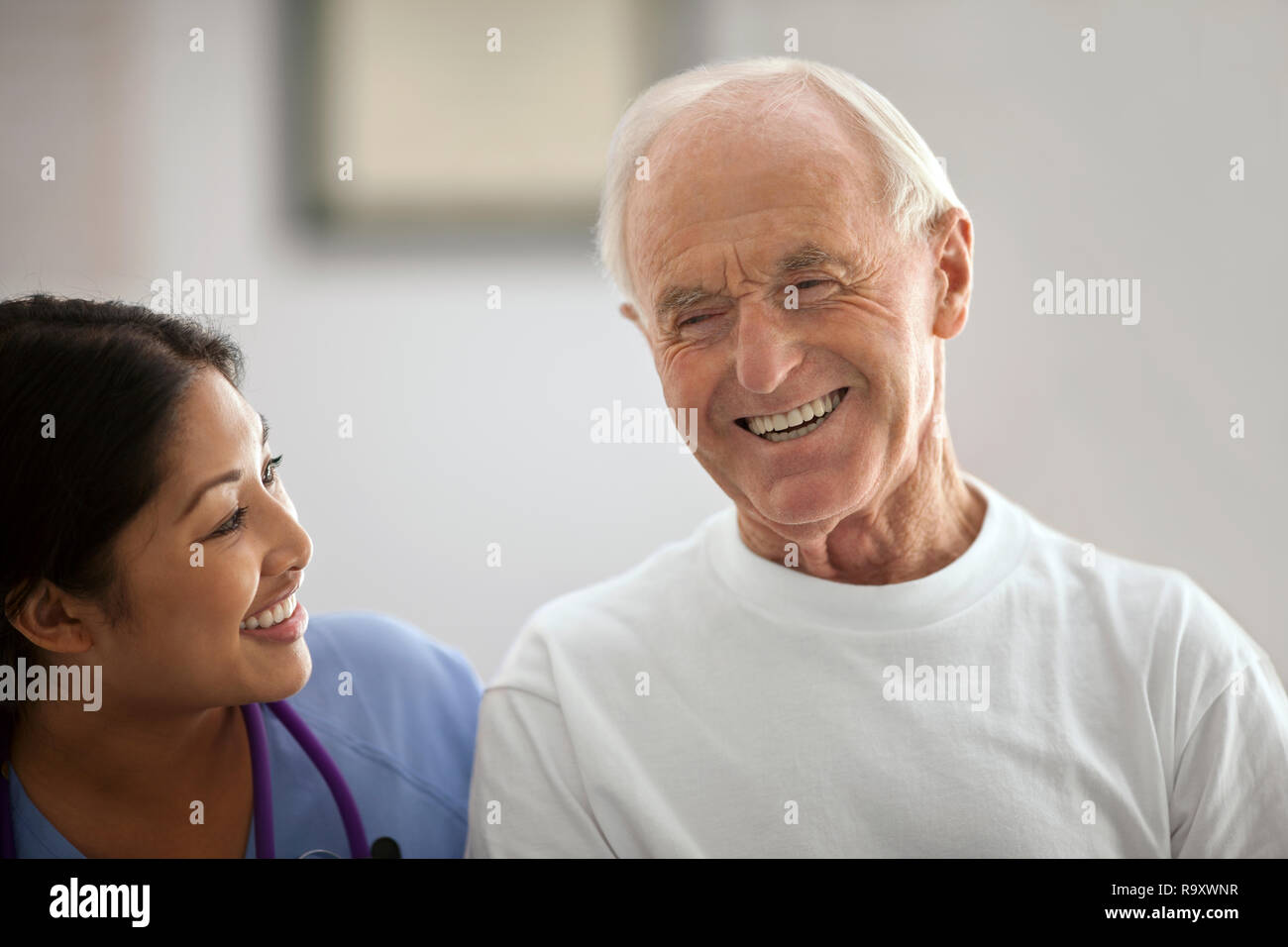 Smiling young nurse laughing with an elderly patient. Stock Photo