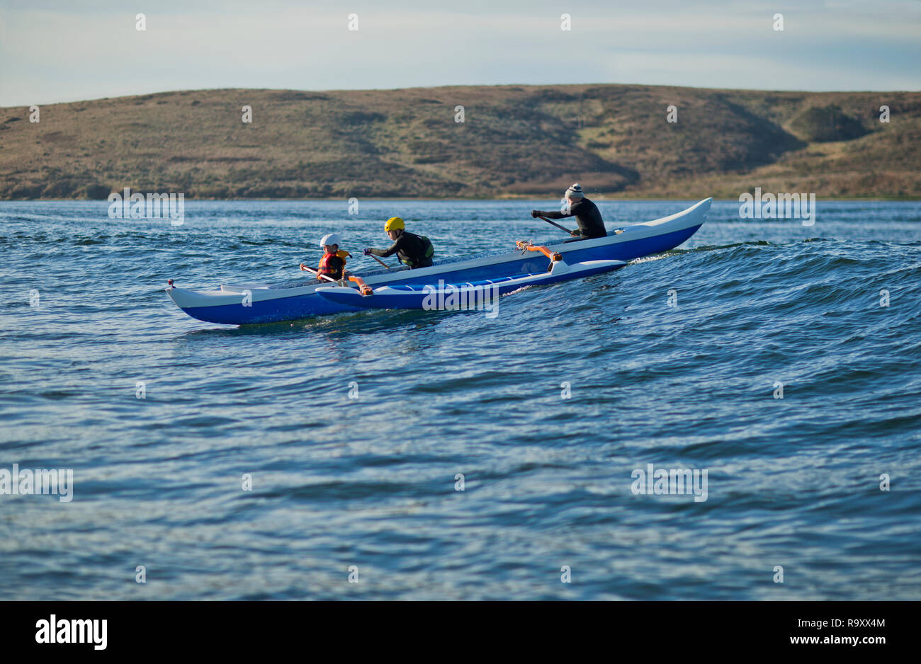 Father and his two sons have fun together paddling a canoe in the ocean. Stock Photo