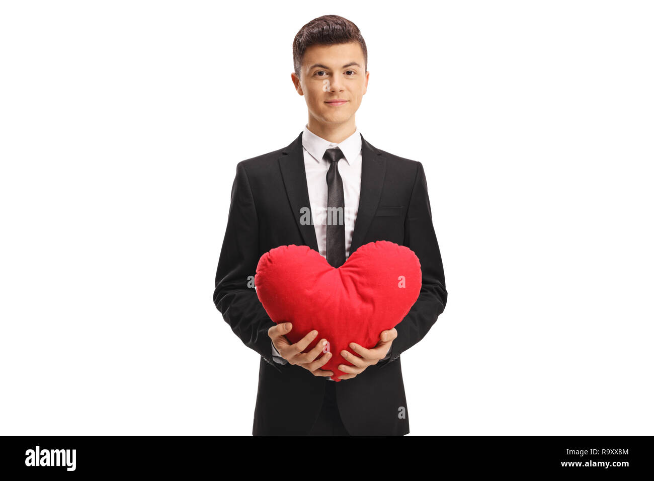 Young handsome man in a suit holding a red heart isolated on white ...