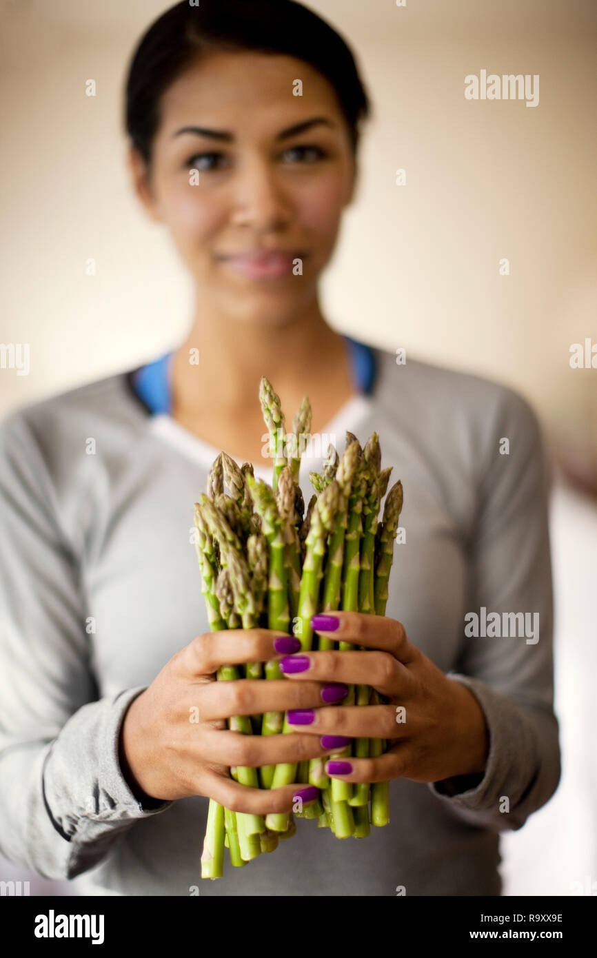 Portrait of a young woman holding a bunch of fresh asparagus. Stock Photo