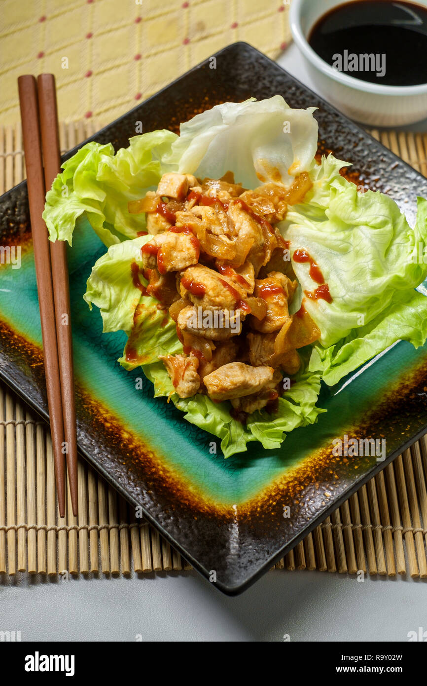 Korean spicy chicken lettuce wrap with gochujang sauce served on bamboo