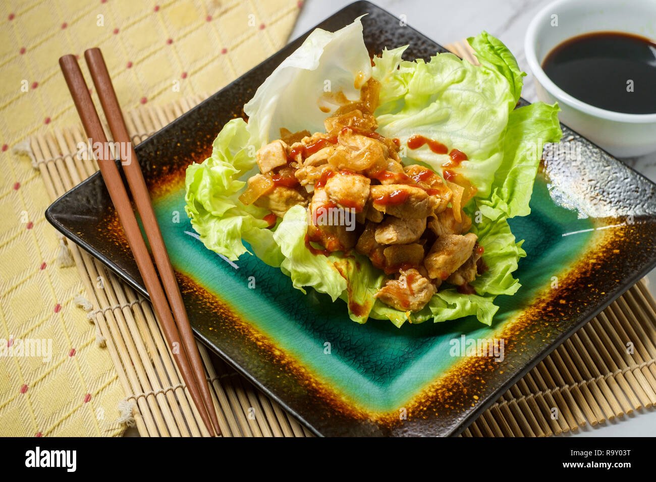 Korean spicy chicken lettuce wrap with gochujang sauce served on bamboo