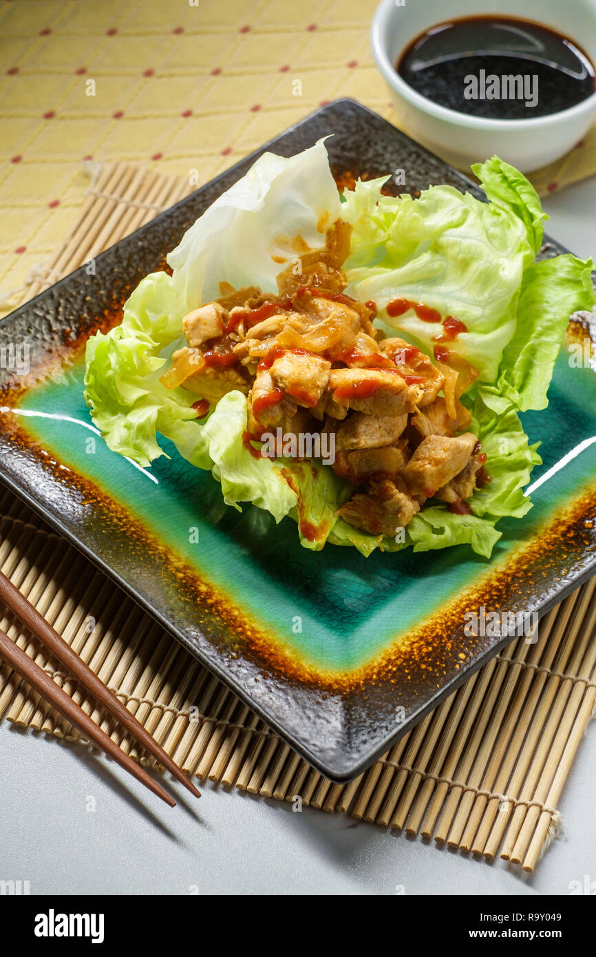 Korean spicy chicken lettuce wrap with gochujang sauce served on bamboo