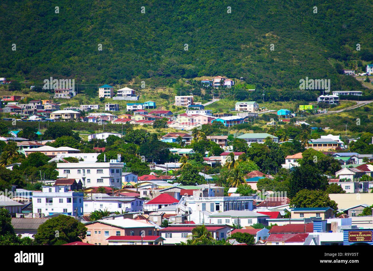 Colorful Rooftops in St Kitts Under Green Hills and Clouds Stock Photo