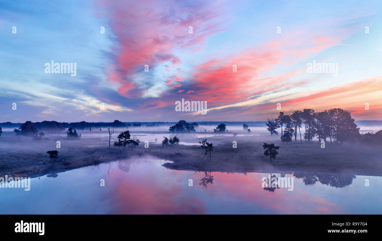 Tranquil wet land at a colorful daybreak with dramatic clouds, Turnhout, Belgium Stock Photo