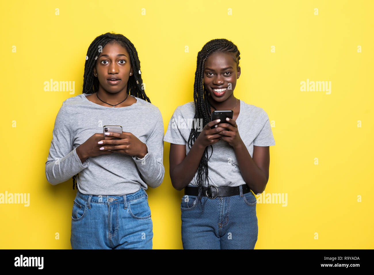 Two african women expressing excitement or surprise while both using ...
