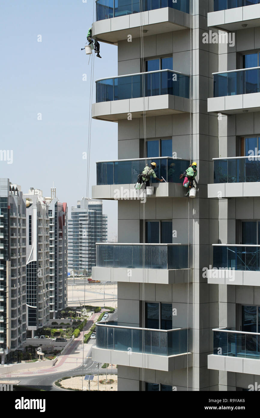 High-rise workers wearing seat belts wash the windows of a high-rise building in Dubai Stock Photo
