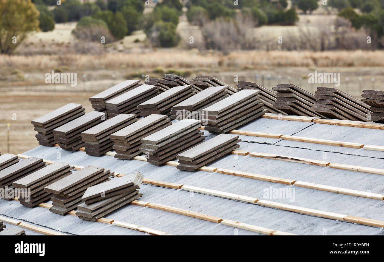 Cement roofing tiles stacked on roof in preparation to lay them Stock