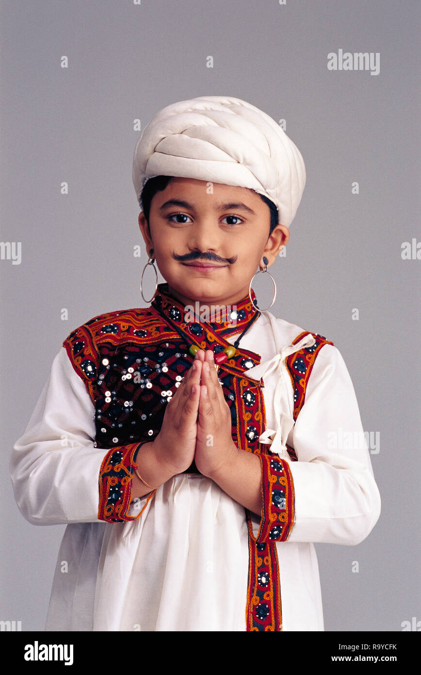 Yound Gujarati boy dressed as an adult famer wearing a traditional outfit with a false moustache, with hands folded Stock Photo