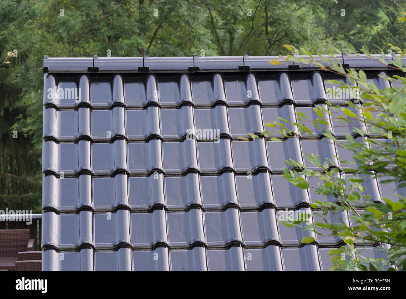 Modern roof with PVC coated black roof tiles with brick effect. Stock Photo
