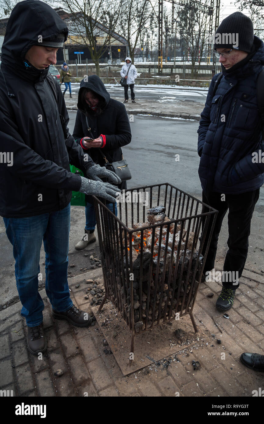28.02.2018, Bytom (Beuthen), Schlesien, Polen - Menschen an einer Bushaltestelle waermen sich an einem Gefaess mit brennender Steinkohle. 00A180228D09 Stock Photo