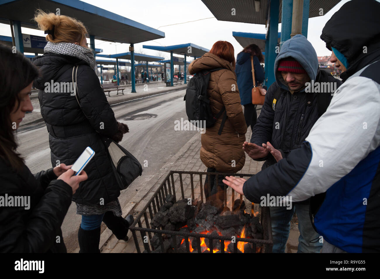 28.02.2018, Bytom (Beuthen), Schlesien, Polen - Menschen an einer Bushaltestelle waermen sich an einem Gefaess mit brennender Steinkohle. 00A180228D14 Stock Photo