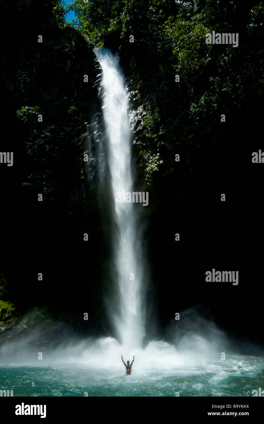 Waterfall, a man standing in the pool at the bottom of the waterfall