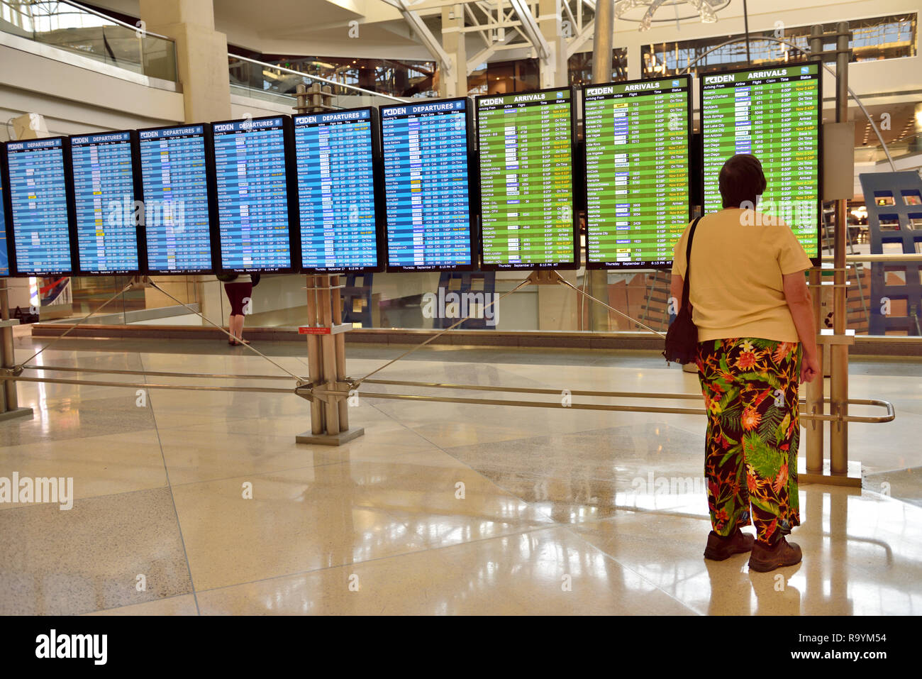 Woman checking the departure, arrivals board at airport, Denver International Airport (DEN), Colorado, USA Stock Photo