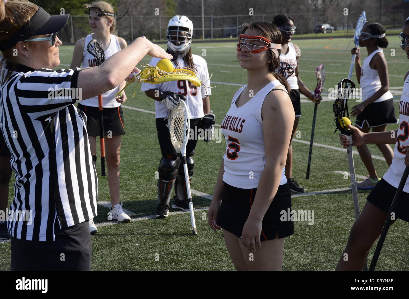 referee examines  a player's lacrosse stick in a high school lacrosse game Stock Photo