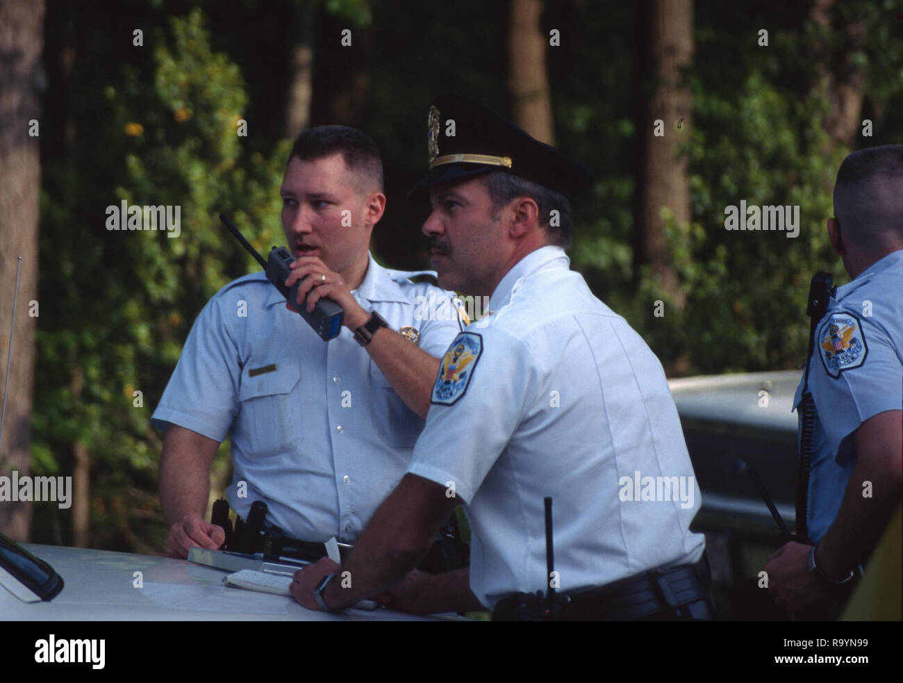 Two policemen one talking on the radio at the scene of an emergency Stock Photo
