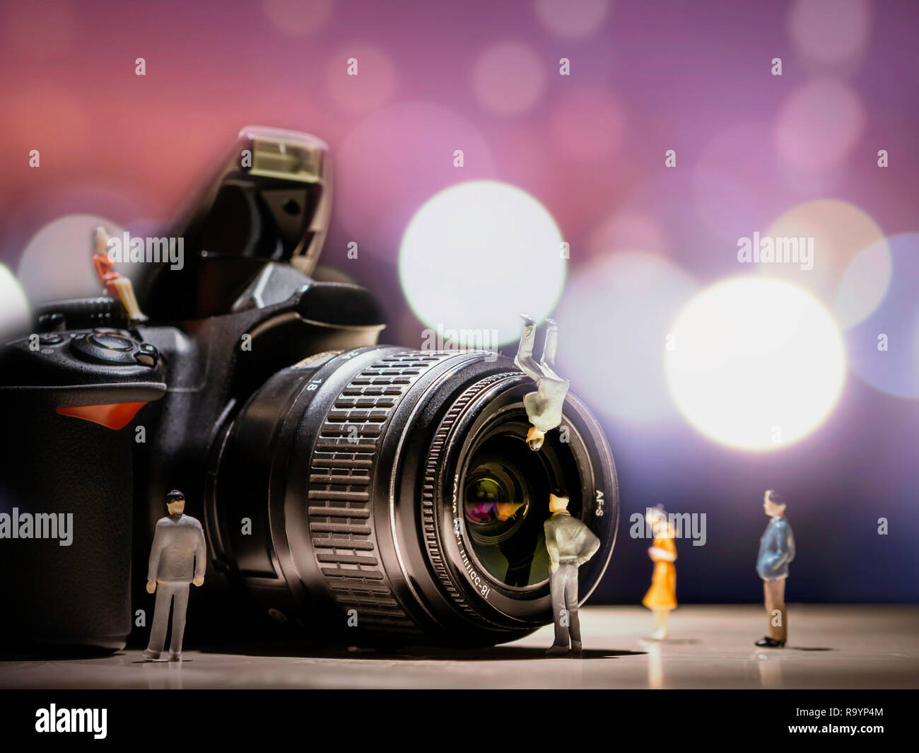 Professional DSLR camera and lens with bokeh background. Small human  figures standing in front of the camera and lens Stock Photo - Alamy