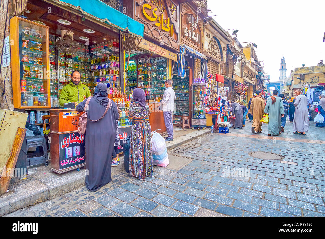 CAIRO, EGYPT - DECEMBER 20, 2017: Two arab ladies in traditional abayas buy perfums at small perfume shop in Khan El-Khalili Market, on December 20 in Stock Photo