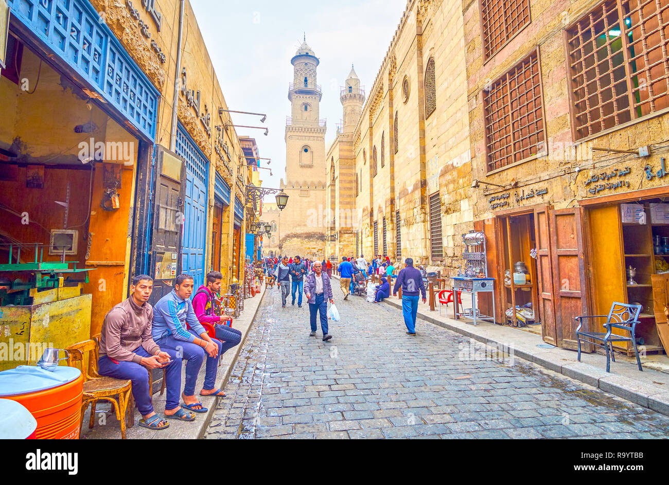 CAIRO, EGYPT - DECEMBER 20, 2017: The merchants from small shop rest sitting on the street with a view on medieval edifices, on December 20 in Cairo. Stock Photo
