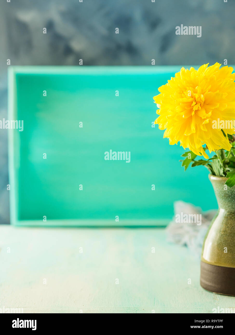 Turquoise Pastel Color Background With Yellow Flower In Vase