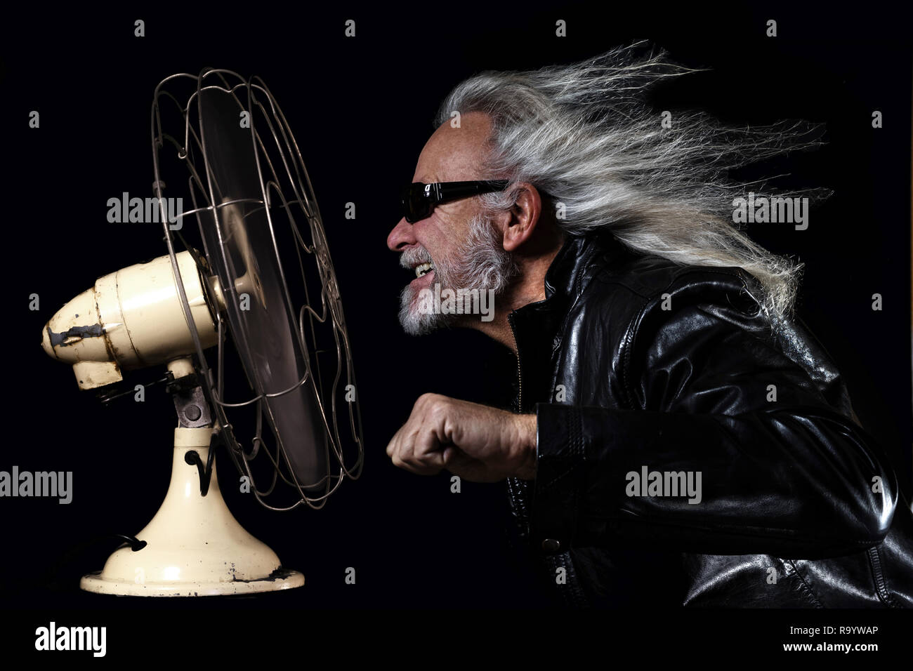 bikers dream. Long-haired man simulates a motorcycle ride in front of a fan. Stock Photo