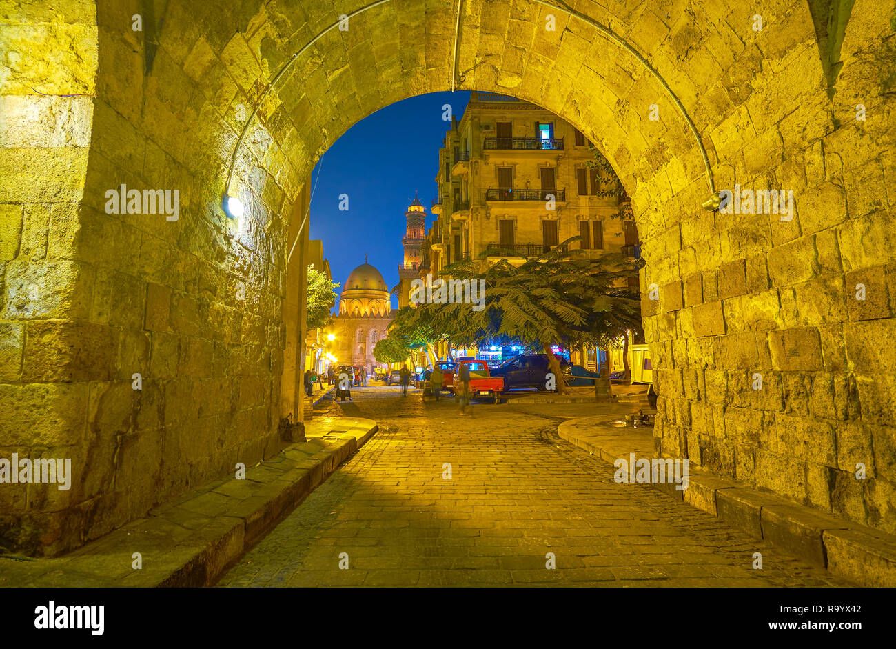 The old archway in old Cairo leads to Al-Muizz street with huge Qalawun complex of the background, Egypt Stock Photo
