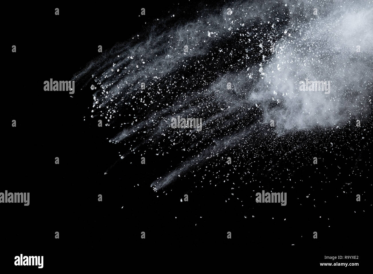Bizarre forms of  white powder explosion cloud against dark background. Launched white particle splash on black background Stock Photo