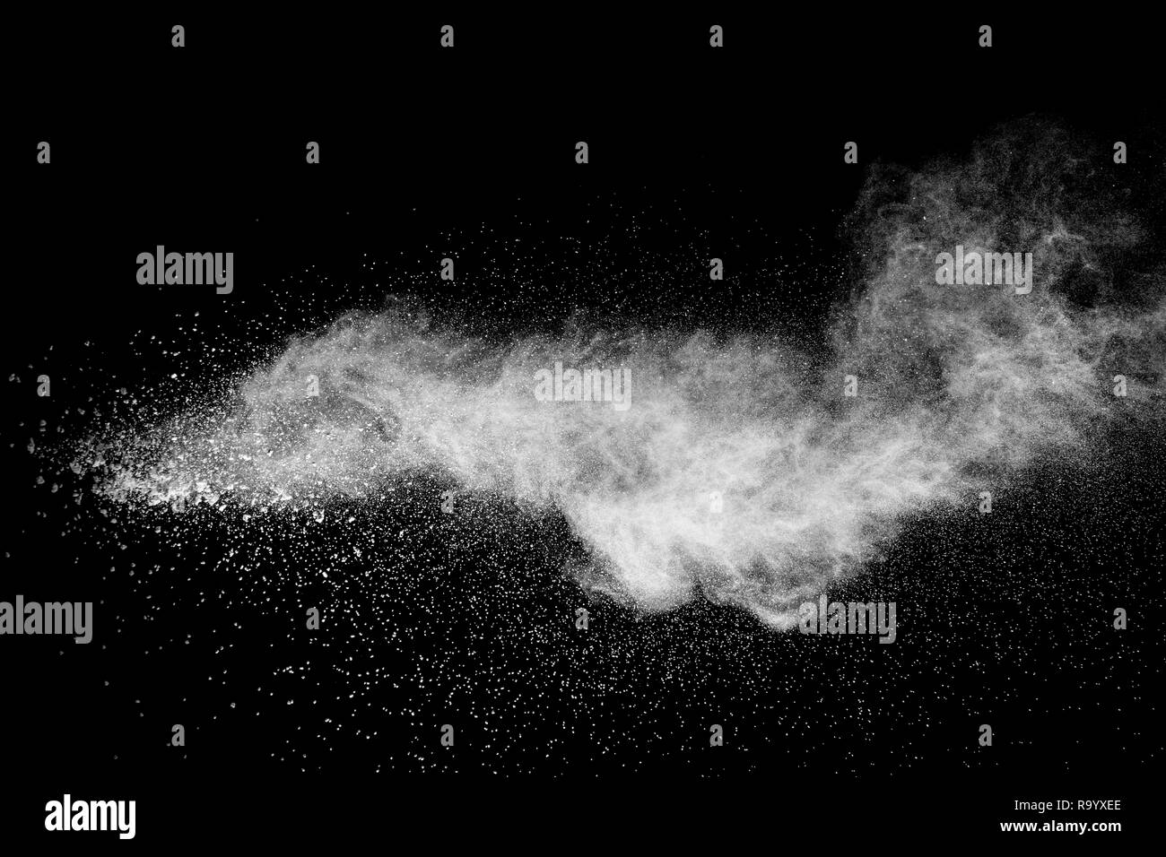 Bizarre forms of  white powder explosion on white background.Launched white dust particles splash on dark background. Stock Photo