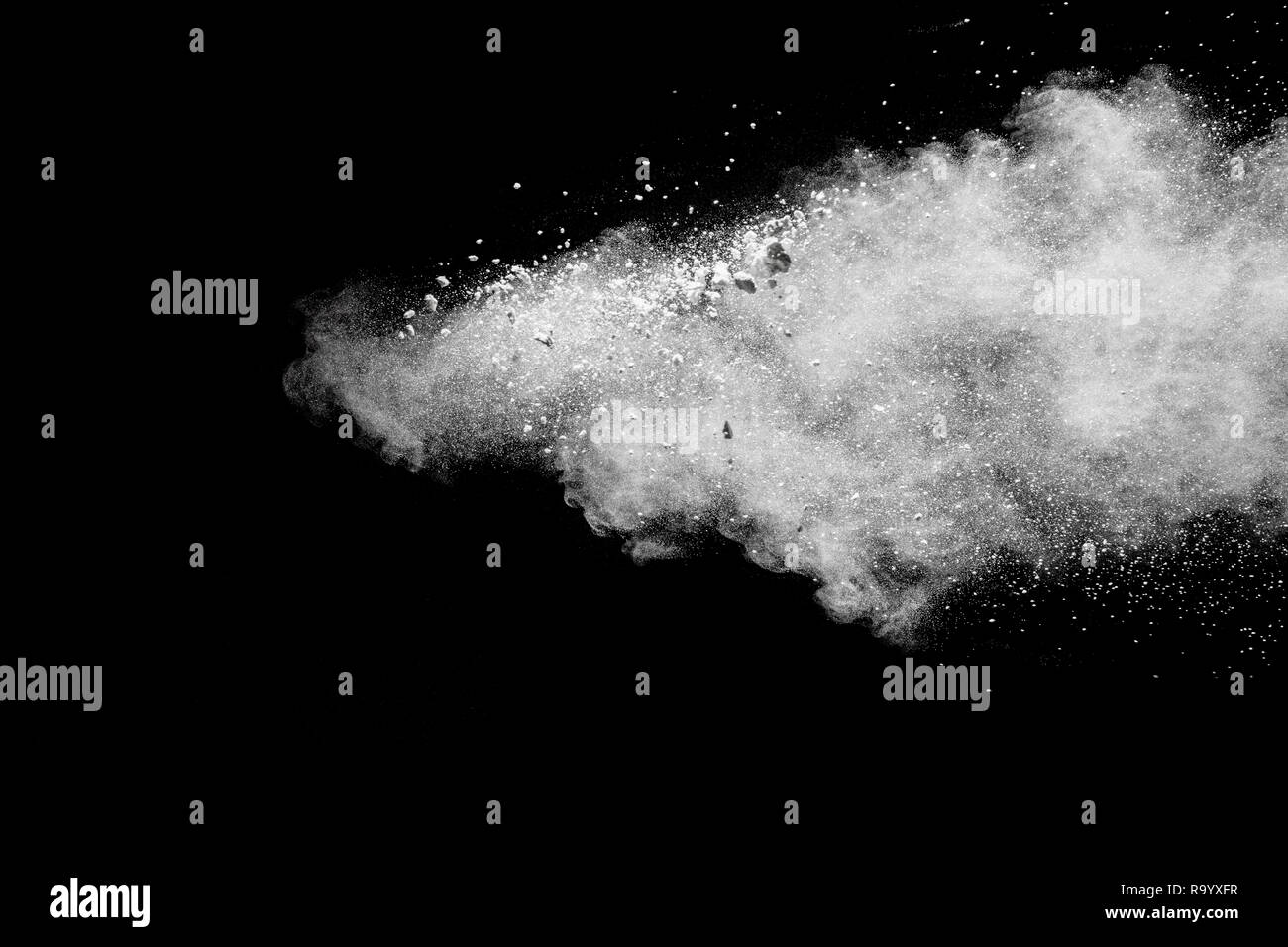 Bizarre forms of  white powder explosion on white background.Launched white dust particles splash on dark background. Stock Photo