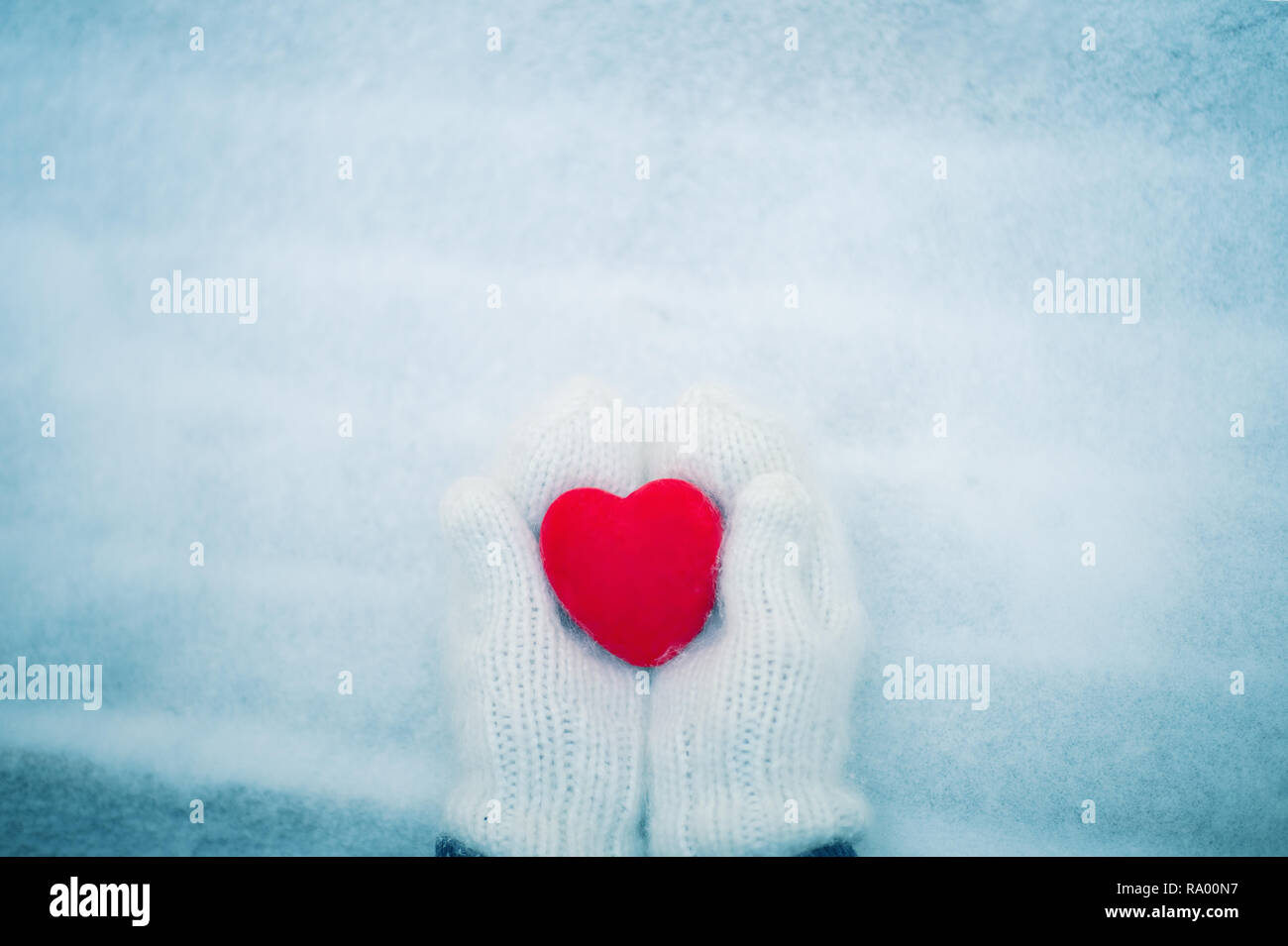 Red heart in woman's hands wearing white woolen mittens. Valentine's Day concept Stock Photo
