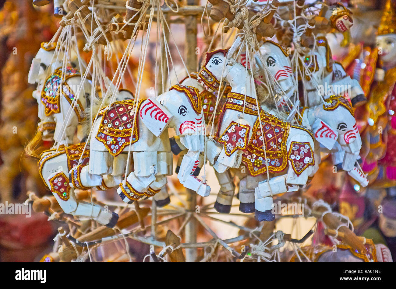 The stand with wooden string puppets- elephants, decorated with paintings, and spangles in souvenir store of Shwe-gui-do quarter, Mandalay, Myanmar. Stock Photo